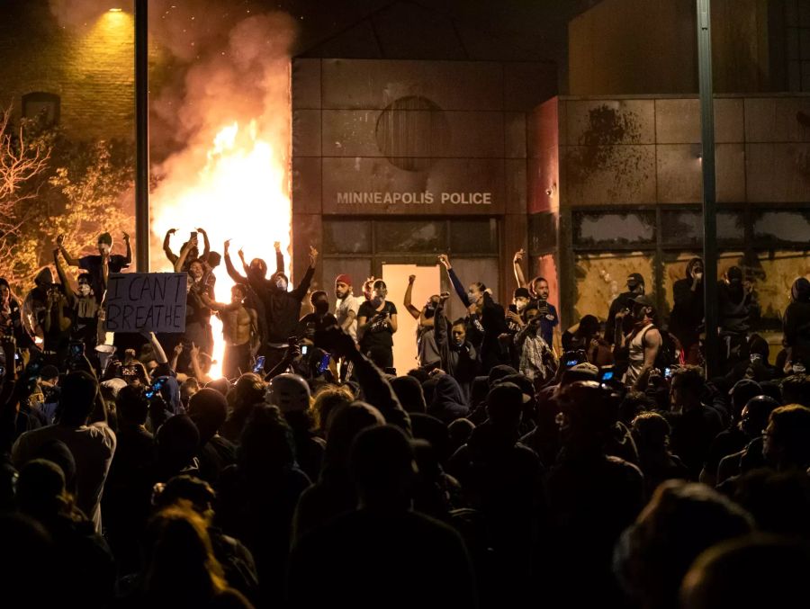 Protestler stehen gestikulierend vor dem brennenden Gebäude des 3. Bezirks der Polizei von Minneapolis nach dem Tod von George Floyd.