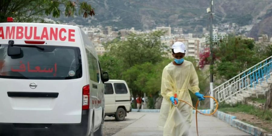 Ein Arbeiter desinfiziert den Weg vor einem Krankenhaus in der Stadt Tais