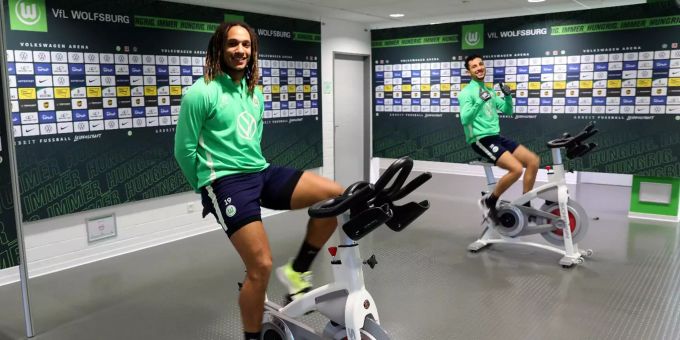 Das von VfL Wolfsburg überlassene Foto zeigt die Spieler Kevin Mbabu (l.) und Ismail Azzaoui, die sich auf Spinningrädern fit halten. Coronavirus - VfL Wolfsburg