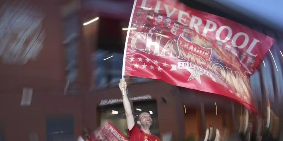 Ein Fan des FC Liverpool schwenkt feiert seinen Verein. Foto: Jon Super/AP/dpa