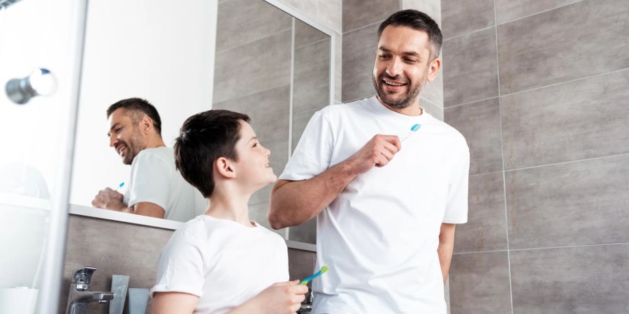 vater und sohn am waschbecken, zähne putzend