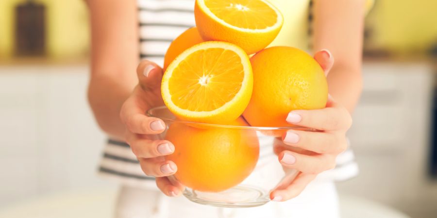 Frau hält eine Schüssel mit Orangen