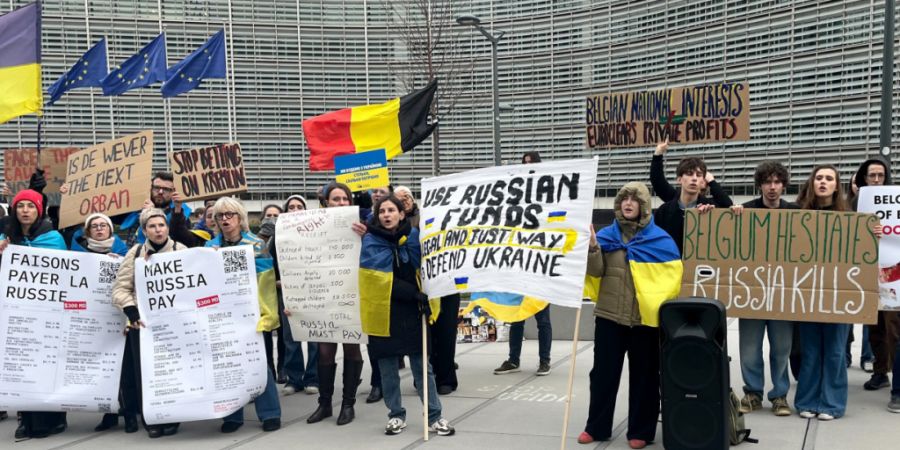 Menschen demonstrieren vor dem EU-Ratsgebäude für die Verwendung von in der EU festgesetztem russischen Geld für die Ukraine. Foto: Katharina Redanz/-/dpa