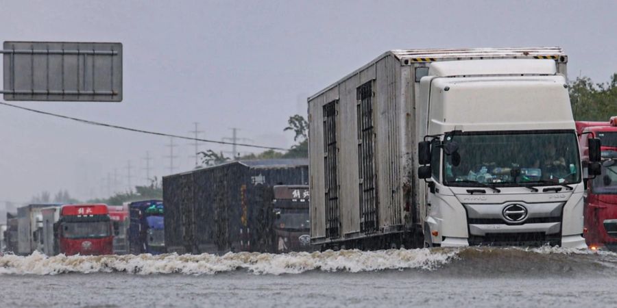 Grosse Lastwagen fahren durch ein Hochwasser in Shenyang in der nordostchinesischen Provinz Liaoning.