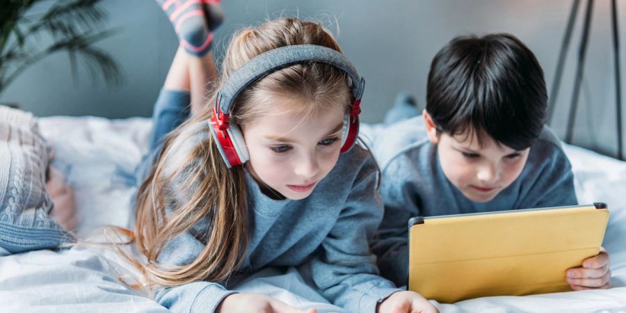 Junge und Mädchen auf dem Bett mit ihren Smartphones