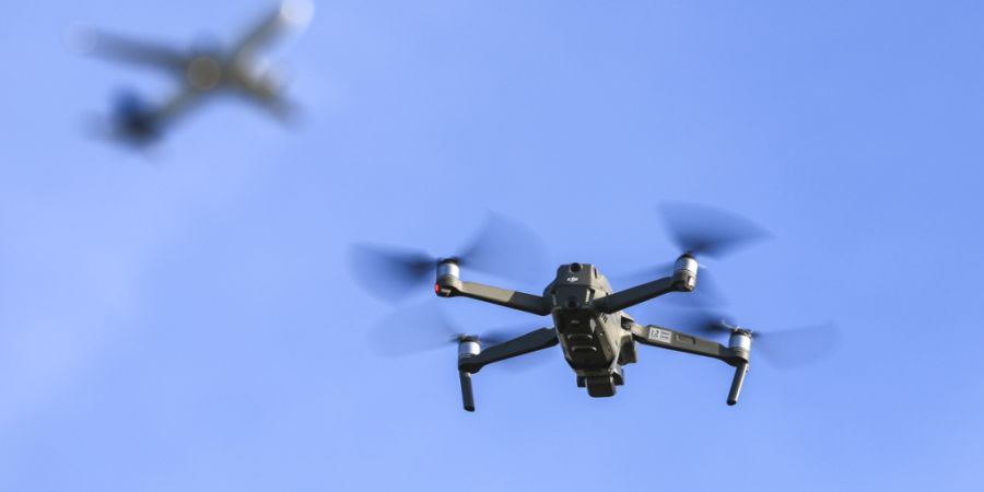 ARCHIV - Eine Drohne fliegt vor einem startenden Flugzeug in der Nähe des Flughafens Leipzig/Halle. Foto: Jan Woitas/dpa