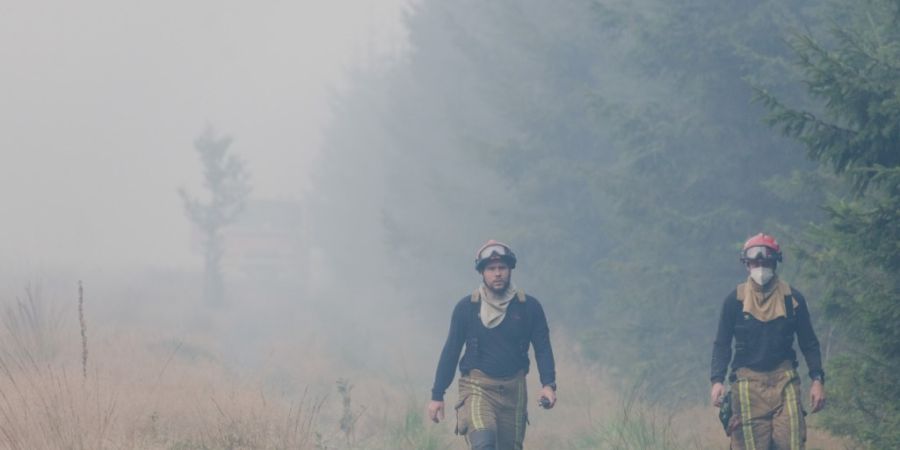 Feuerwehrleute gehen im Waldbrandgebiet. Im Naturschutzgebiet Hohes Venn nahe der deutschen Grenze wütet ein Großbrand. Foto: Nicolas Lambert
