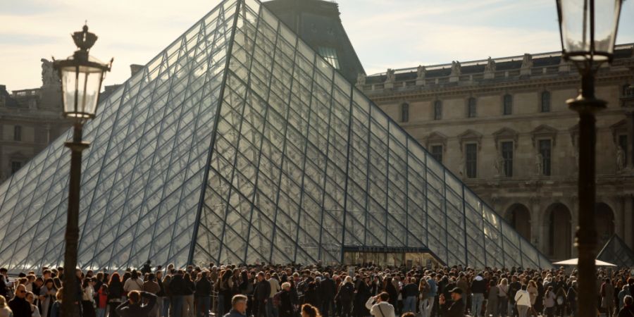 ARCHIV - Menschen stehen Schlange vor dem Louvre-Museum. Neun Monate nach dem spektakulären Einbruch öffnet die Einrichtung wieder die Galerie d'Apollon. Foto: Thomas Padilla/AP/dpa