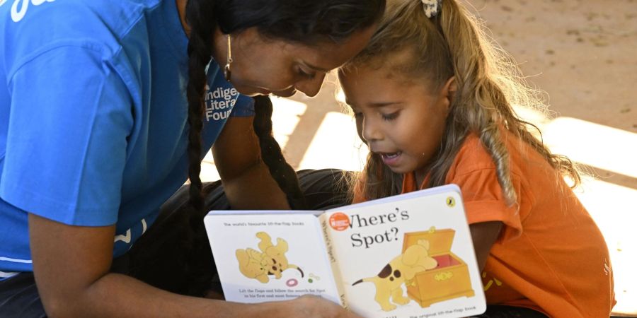 Eine Mitarbeiterin der australischen Lese-Stiftung Indigenous Literacy Foundation (ILF) liest ein Buch zusammen mit einem Kind.