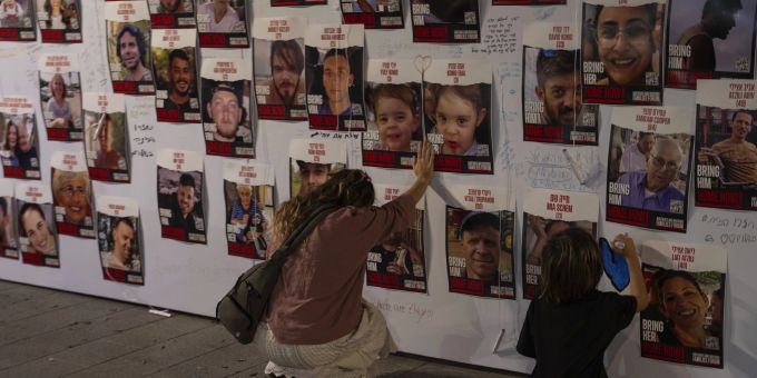 Eine Frau berührt Fotos von Israelis, die in Gaza vermisst und gefangen gehalten werden, an einer Wand in Tel Aviv am 21. Oktober 2023. Israel Geiseln Hamas