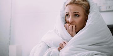 Frau in Bettdecke, ängstlich