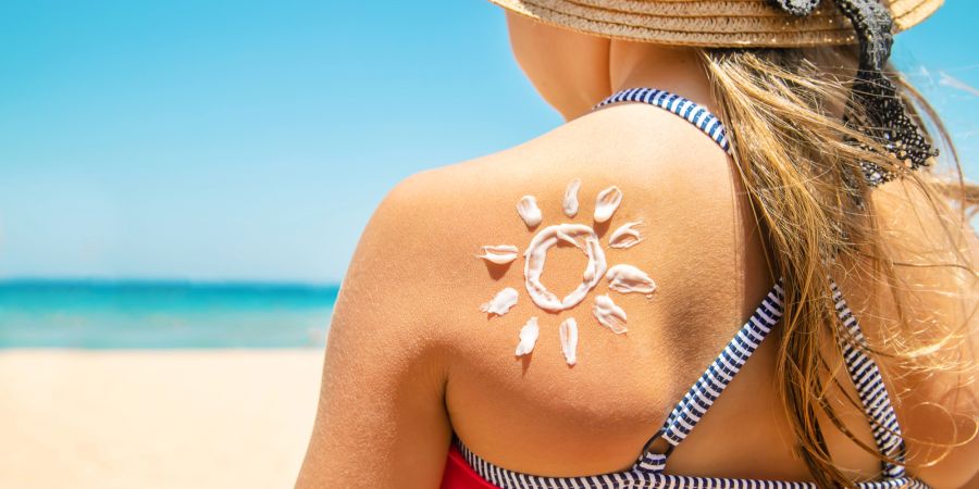 Rücken eines Mädchens, auf dem mit Creme eine Sonne gezeichnet wurde