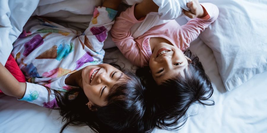 Kinder lachend im Bett