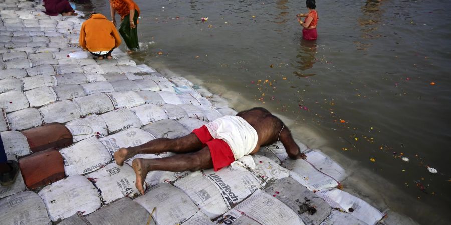 Ein Teilnehmer des Pilgerfests Maha Kumbh Mela spricht ein Gebet, bevor er ein Bad im Fluss nimmt.