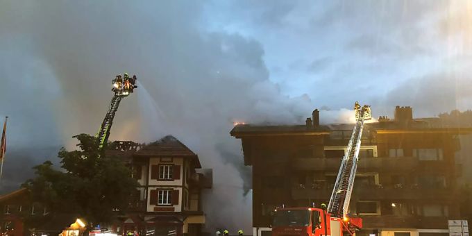 Die Feuerwehr bekämpft von Drehleitern aus die Brände im Wohn- und Geschäftsgebäude und im Mehrfamilienhaus. Zweisimmen BE