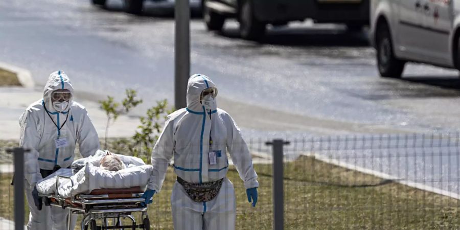 ARCHIV - Medizinische Mitarbeiter transportieren einen Patienten mit Verdacht auf Covid-19 auf dem Gelände eines Krankenhauses bei Moskau. Foto: Alexander Zemlianichenko/AP/dpa