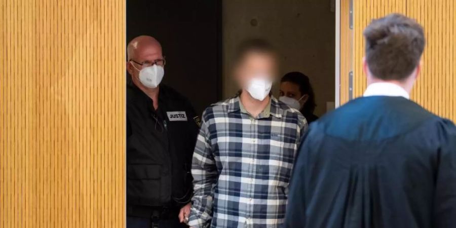 Der Angeklagte (im karierten Hemd) wird in den Sitzungssaal geführt. Foto: Sven Hoppe/dpa