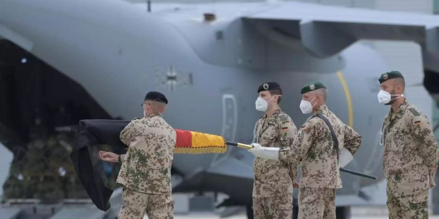 Brigadegeneral Ansgar Meyer (l), der letzte Befehlshaber der Bundeswehr in Afghanistan, rollt vor dem Transportflugzeug vom Typ Airbus A400M der Luftwaffe die Truppenfahne ein. Foto: Hauke-Christian Dittrich/dpa-Pool/dpa