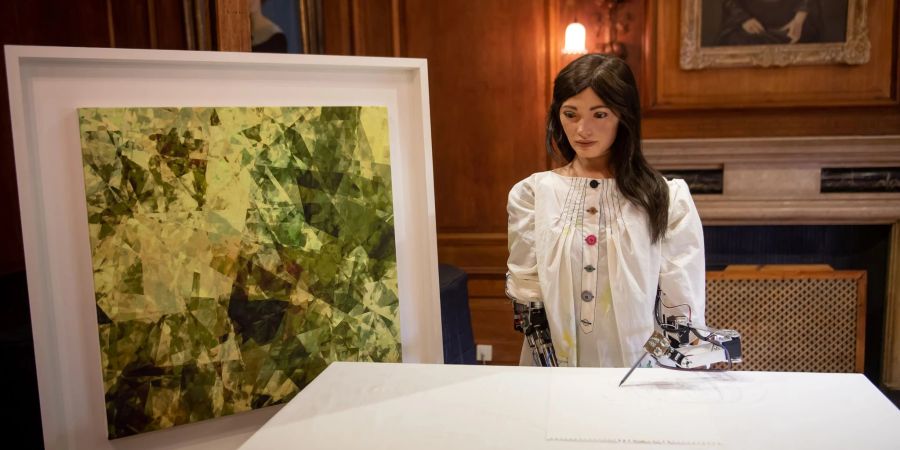 Ai-Da, die weltweit erste Roboterkünstlerin, steht während ihrer Vorstellung auf einer Pressekonferenz am Lady Margaret Hall College der Oxford University neben einem eigenen Kunstwerk.