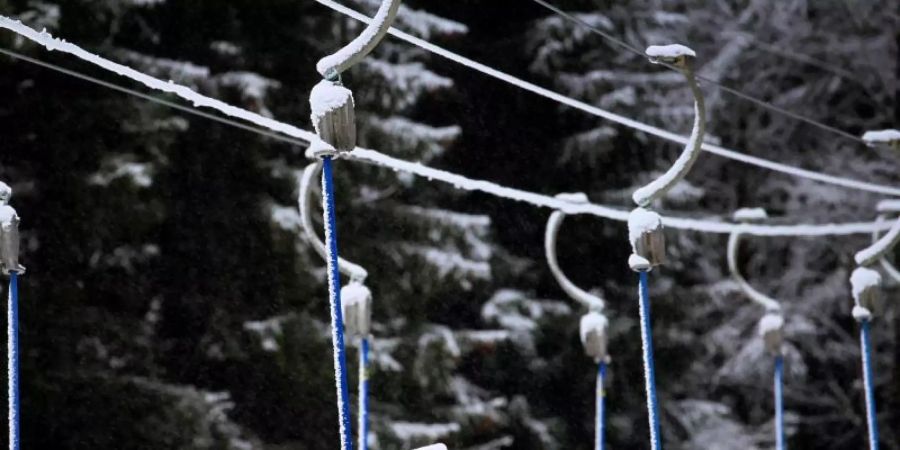 Bügel eines Schleppliftes hängen in schneebedeckter Landschaft. Wegen der Massnahmen um das Coronavirus müssen Skilifte geschlossen bleiben. Foto: Karl-Josef Hildenbrand/dpa