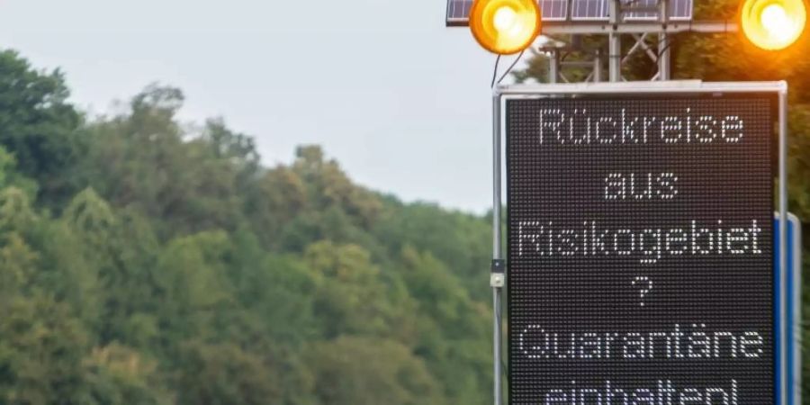 Auf der Autobahn A7 werden Reisende aus Risikogebieten mit einer Leuchttafel "Rückreise aus Risikogebiet? Quarantäne einhalten!" auf die notwendigen Quarantänemassnahmen hingewiesen. Foto: Stefan Puchner/dpa
