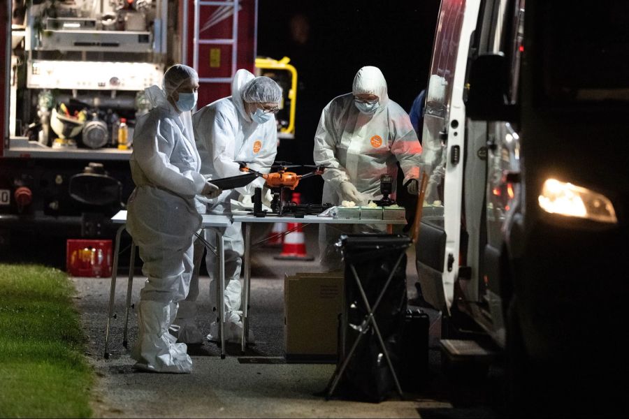 Mitarbeiter der Spurensicherung stehen nach dem Fund einer Frauenleiche an ihren Einsatzfahrzeugen.