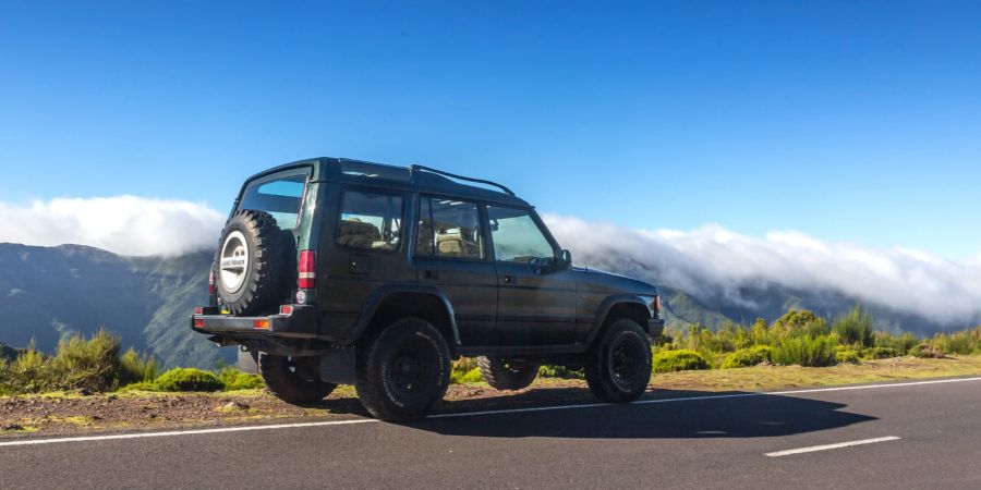 Ein Jeep vor Bergkulisse im Nebel.