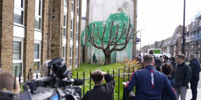 Menschen betrachten ein neues Banksy-Gemälde an einer Wand in London, Montag, 18. März 2024 Hauswand Banksy