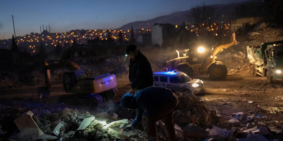 Menschen suchen nach persönlichen Gegenständen in den Trümmern eines zerstörten Gebäudes in Kahramanmaras.