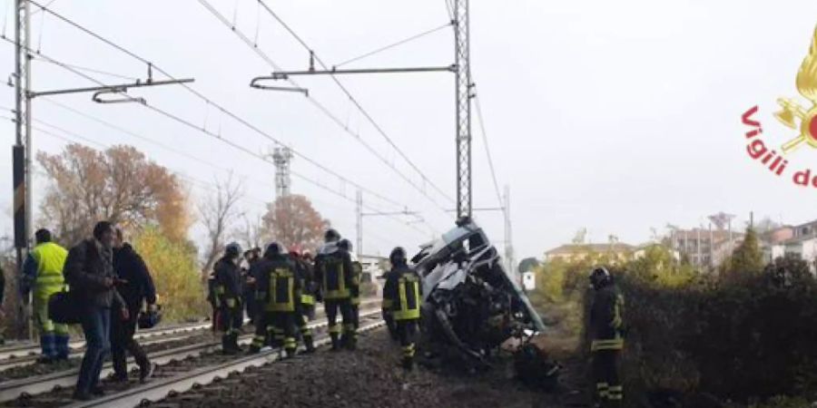 HANDOUT - Handout der italienischen Feuerwehr zeigt einen Blick auf die Unfallstelle. Ein Kleinbus war von der Fahrbahn abgekommen, auf Bahngleise geraten und von einem Zug erfasst worden. Bei dem Unfall in der Nähe der Stadt Parma kam einer der vier Insassen, ein Junge, ums Leben, wie die Feuerwehr mitteilte. Foto: -/Vigilfuoco.it/dpa - ACHTUNG: Nur zur redaktionellen Verwendung im Zusammenhang mit der aktuellen Berichterstattung und nur mit vollständiger Nennung des vorstehenden Credits