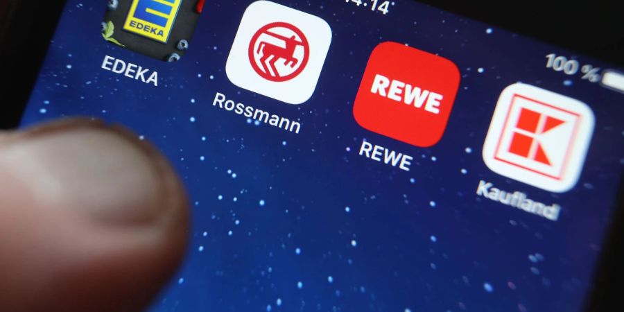 Icons der Apps von den Handelsketten wie Edeka, Rossmann und REWE auf dem Display eines iPhones.