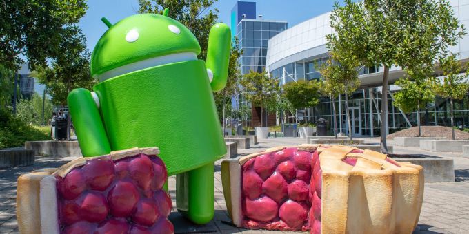 Ein Android grüsst, eingerahmt von Fruchtkuchen, vor der Google-Zentrale. Android Google Fruchtkuchen Gebäude Zentrale