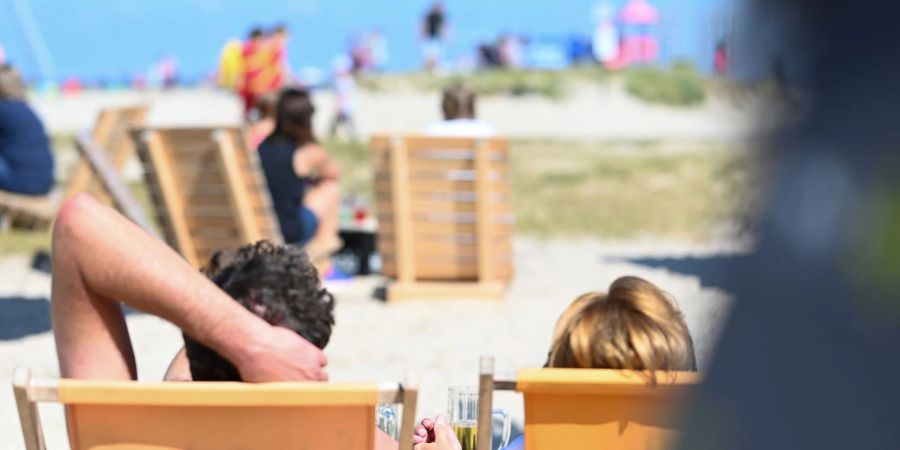 Zwei Gäste der Beachbar am Naturstrandt geniessen den Blick auf die Nordsee bei einem Kaltgetränk.