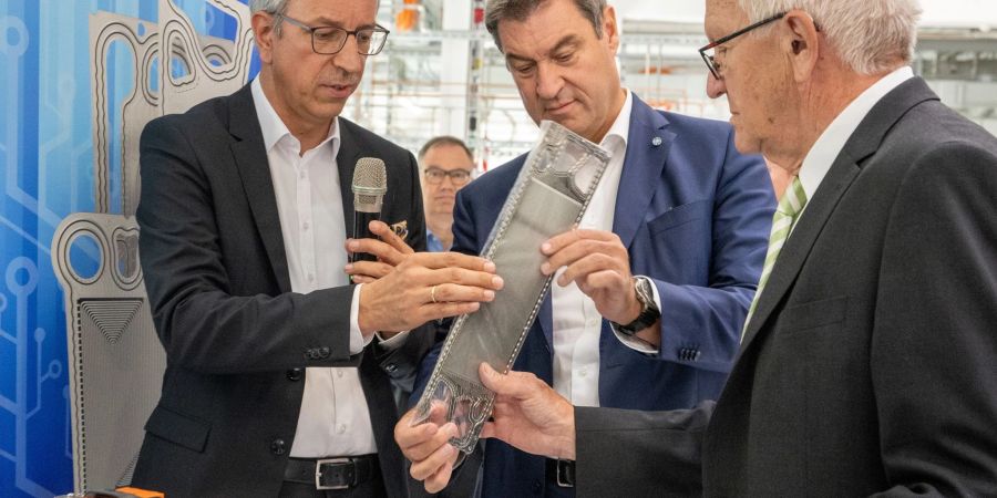 Baden-Württembergs Ministerpräsident Winfried Kretschmann (Grüne, r) und sein bayerischer Amtskollege Markus Söder (CSU, M) lassen sich im Ulmer Zentrum für Sonnenenergie- und Wasserstoff-Forschung von Vorstandsmitglied Markus Hölzle eine Brennstoffzelle zeigen.