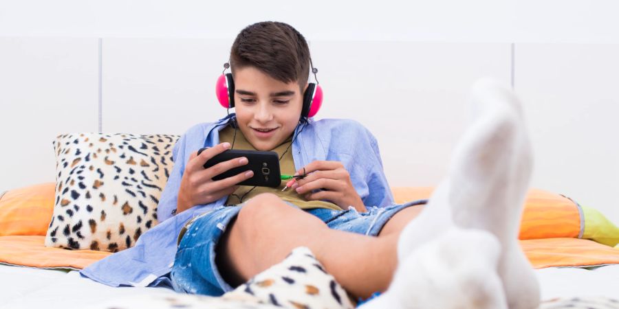 Teenager auf dem Bett am Smartphone