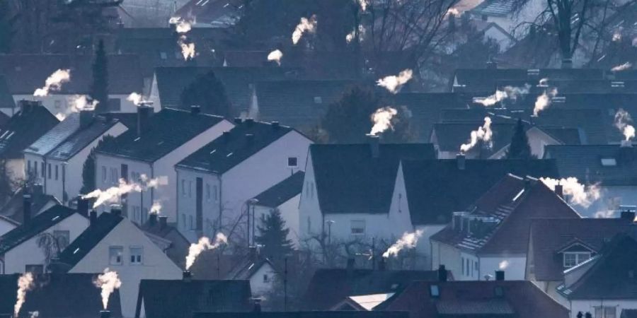 Schornsteine rauchen auf den Dächern der Häuser. Im Herbst sollen konkrete Massnahmen und Gesetze für mehr Klimaschutz kommen. Foto: Armin Weigel/Archiv