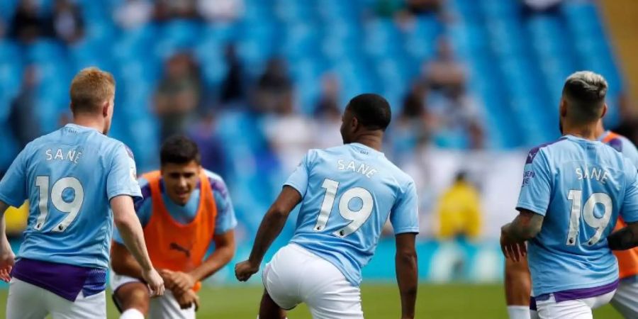 Kevin de Bruyne (l-r), Raheem Sterling und Nicolas Otamendi tragen das Trikot des verletzten Leroy Sané. Foto: Martin Rickett/PA Wire