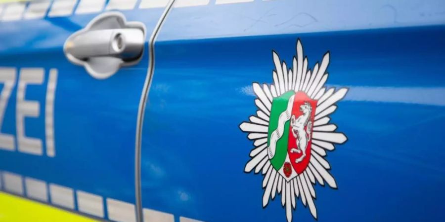 Blick auf ein Emblem der Polizei in NRW an einem Polizeiauto. Foto: Friso Gentsch/Archivbild