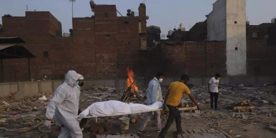 Familienmitglieder und Freiwillige tragen den Leichnam eines Corona-Opfers zur Einäscherung. Foto: Amit Sharma/AP/dpa/Archivbild