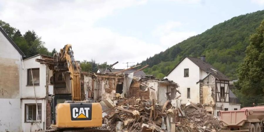 Ein Bagger reisst in Altenburg (Rheinland-Pfalz) Häuser ab, die durch die Flutkatastrophe zerstört wurden. Foto: Thomas Frey/dpa