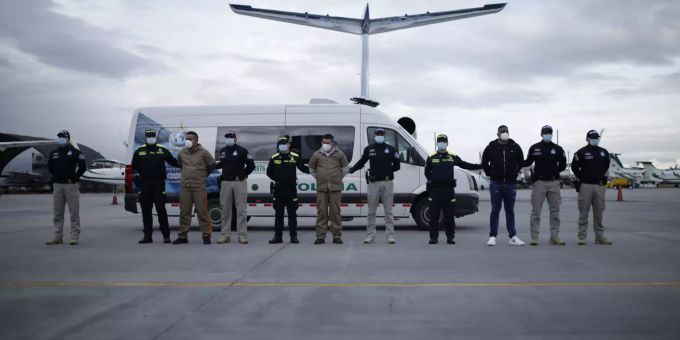 Mitglieder der Guerillagruppe ELN und des Bloque Calima stehen auf einem Flugplatz neben Sicherheitskräften von Interpol, bevor sie an die USA ausgeliefert werden. Extradition of members of Colombian armed groups to the USA
