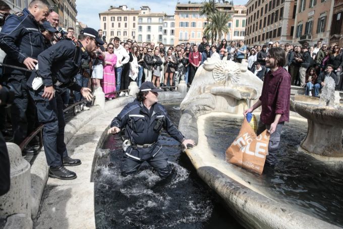 Ein Polizist betritt die «Fontana della Barcaccia» um einen Umweltaktivisten während einer Protestaktion festzunehmen. letzte generation rom