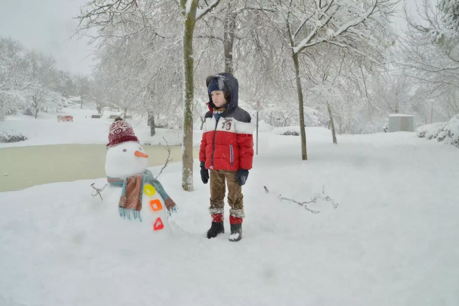 Ein kleiner Junge blickt auf einen Schneemann.