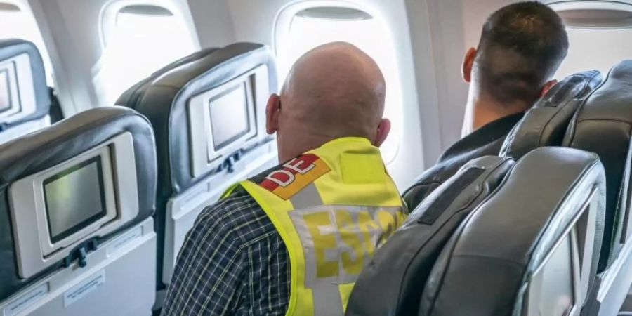 Ein Polizeibeamter begleitet einen Afghanen als «Escort» auf dem Flug nach Kabul (Archiv). Foto: Michael Kappeler/dpa/Archiv