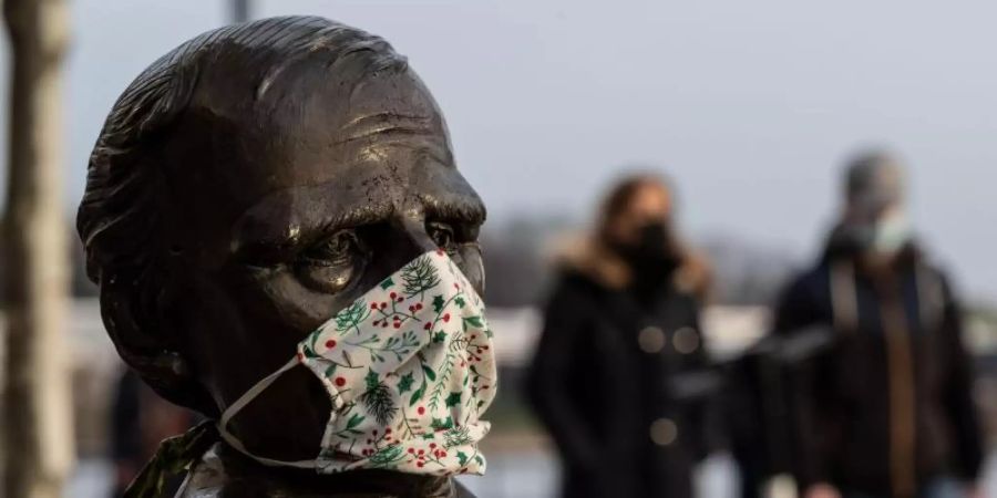 Ein Mund-Nasen-Schutz an einer Statue am Dortmunder Phoenix-See. Foto: Bernd Thissen/dpa