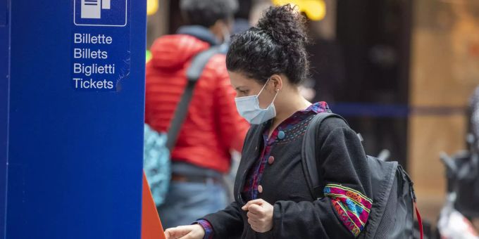 Eine Reisende kauft sich mit Mund-Nasen-Schutz in einem Bahnhof ein Ticket. Coronavirus - Schweiz