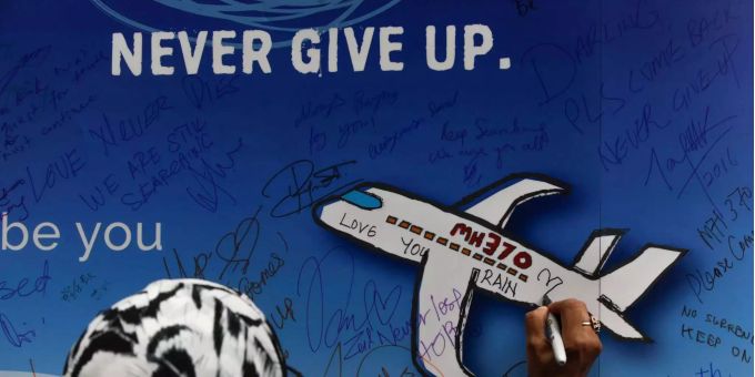Eine Frau schreibt während einer Gedenkveranstaltung zum Malaysia Airlines Flug 370 eine Nachricht auf ein Banner. Malaysia Airlines Flug 370