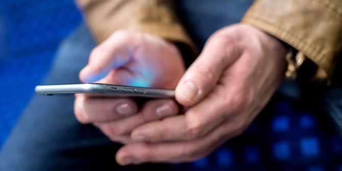 Ein Mann hält ein Smartphone in den Händen.