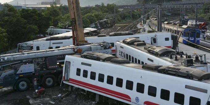 Ein Zug (r) passiert entgleiste Zugwaggons, die neben den Gleisen stehen und liegen. Ein Zug (r) passiert entgleiste Zugwaggons, die neben den Gleisen stehen und liegen.