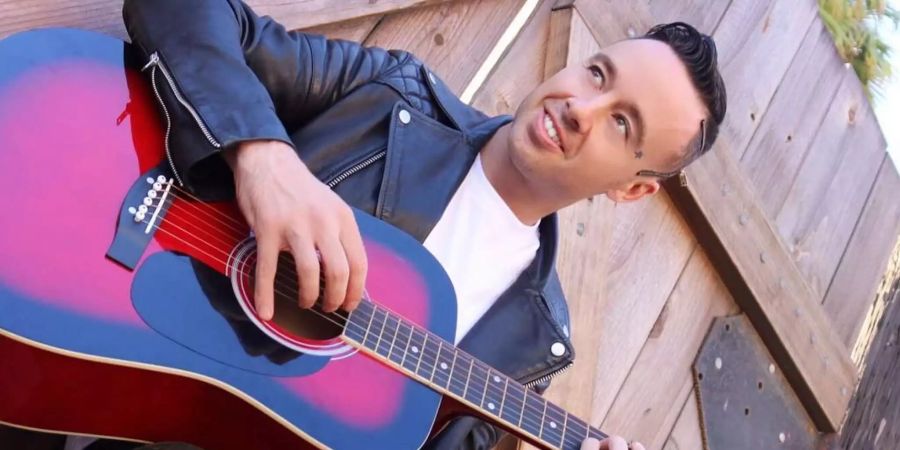 Jon James posiert mit seiner Gitarre für die Kamera.